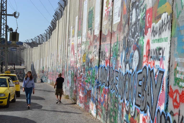 イスラエルのエルサレムからバスに乗って、 パレスチナのベツレヘムへ行った。 到着すると、人がわんさかしていて、 マーケットも賑わいがあって、いい街だ。 イスラエルとパレスチナ自治区の間には、 高さ６m以上の、人間がかんたんには 超えられない壁が隔てられている。 壁の上には、つめたい有刺鉄線が パレスチナ側を向いている。 じっさいに壁の横を歩いてみると、圧迫感があって、 壁を建てられた側のパレスチナ人の気持ちは、 けっして、うれしくないのがわかる。 キリストの生まれたとされる場所に行った後、 タクシーのおじさんがストリートアーティスト バンクシーの６つのウォールペイントに 連れて行ってくれるというので、 値段交渉をして、タクシーに乗った。 おじさんに「来るのはじめて？」と聞かれ、 「うん、イスラエルはじめて。」と言ったら 「ここはパレスチナだーよー。 イスラエルはクレイジーだーよー。」と、 つっこまれてしまった。し、しまった。 そんなおじさんに、訪ねてみた。 「イスラエル人の友だちはいるの？」と。 「いっぱいいるよ。」とおじさんが言う。 ああ、よかった。そのことばは、 壁の隙間に見える小さなヒカリに思える。 友だちという存在は、最後の最後で、 争いを止める防波堤になると思う。 ぼくだったら、友だちの住んでいる場所に ミサイルなんかの攻撃はぜったいにできない。 バンクシーのウォールペイント３つを回ると、 「はい、おわり。お金ちょうだい。」と、 急にタクシーを止める、おじさん。 「えっ、６つまわるって言ってたじゃん。」 と、ぼくがつっこむ。 「他の３つは遠いね。」と、ごまかすおじさん。 「人をだますのは、よくないなあ。 最初に言って金額は、払いたくない。 ６つのうちの３つしか見てないから、半分ね。」 と、しかたなくお金を払おうとするぼく。 お金をうけとらないおやじ。 （おじさんと、「さん」づけするのをやめる） 「おれには、子どもがいるんだ。」 「子どもにも同じことをするのかい？」 そして、唾飛ばしながら５分ほど口喧嘩が続く。 なんかのやりとりがきっかけで、 「神は見ている。」と言い出すおやじ。 「人をだましてるあなたのことも、 神さまは見てるんだよ。」と、ぼくが言うと、 しまったという顔をして半額を受けとるおやじ。 前に、アルメニアの旅で会った日本人と、 「戦争は、おわらないのか？」という 話になって、彼は「戦争の最小単位である ケンカがおわらないのだから、戦争も、 おわらないんじゃないか」と言っていた。 ぼくは、そのとき、何も言わなかったんだけど、 今は、たとえケンカをしたとしても、 相手のことを殴らないでいることはできる。 と思っている。 どちらかが殴りはじめたら、 そこから悪循環がはじまってしまう。 互いにケンカをはじめない智慧をもち、 もしケンカがはじまっているのだとしたら、 それ以上に膨らまない工夫をすること。 そうすれば、戦争までにはいかない。 それがぼくの子供のような考えだ。 それでは、今日も、明日も、明後日も、いい１日を。 なんだって工夫ってのが必要だよね。 このときの場所／パレスチナ ベツレヘム 現在地／マダガスカル にほんブログ村の「旅行ブログ」に参加しています。 よかったら、「見たよ」のあかしに、世界一周バナーをクリックして下さい。 　１日１回のクリックが応援になる仕組みです。 [alert]感想を送る[/alert]